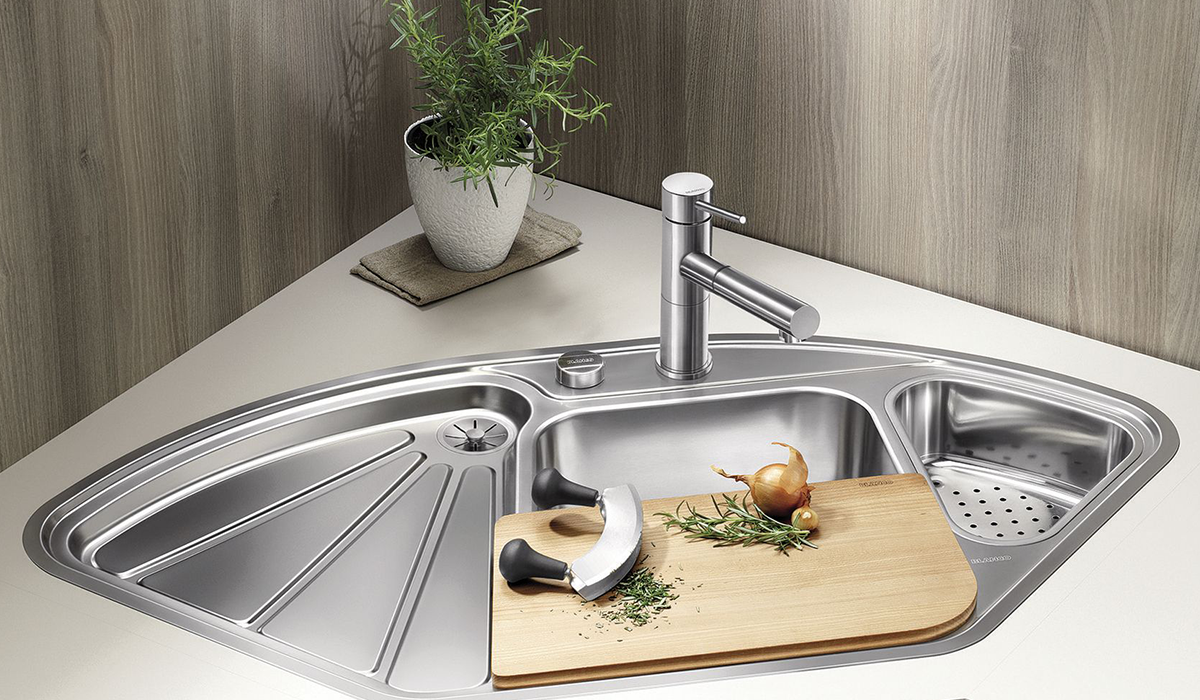 in the kitchen there is a stainless steel sink with 3 different compartments